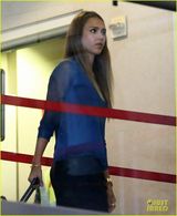 组图：阿尔芭憔悴亮相机场 肩夹手机忙通话