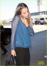 组图：阿尔芭憔悴亮相机场 肩夹手机忙通话