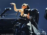 组图：Lady Gaga豪放坐汽车表演 夸张弹琴显丰满