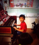 组图：Lucas领弟弟逛乐器行 弹琴扮指挥架势足