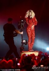 组图：Rita Ora撑黑伞演出 红色蕾丝连身裤秀身段