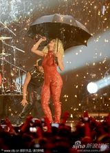 组图：Rita Ora撑黑伞演出 红色蕾丝连身裤秀身段